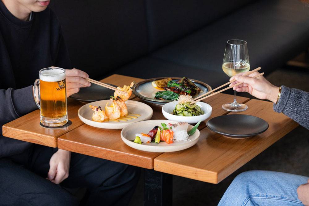 Guests enjoying sushi, sashimi and shared Japanese dishes with beer and wine at Zushi restaurant