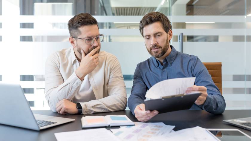 Business owner reviewing financial documents with an adviser while discussing business structure, tax planning and future financial decisions.